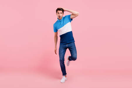 Full length photo of impressed brunet millennial guy go wear polo jeans sneakers isolated on pink backgroundの写真素材