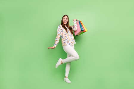 Full size photo of crazy brunette hairdo young lady with bags wear blouse trousers sneakers isolated on green backgroundの写真素材