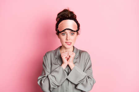 Portrait of attractive worried girlish girl wearing pajama wake-up time isolated over pink pastel color backgroundの写真素材