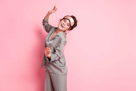 Portrait of attractive cheerful carefree girl wearing pajama dancing having fun isolated over pink pastel color backgroundの写真素材