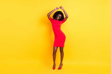 Full length photo of shiny sweet dark skin lady dressed red outfit glasses dancing isolated yellow color backgroundの写真素材