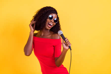 Photo of young beautiful stunning positive afro girl in sunglasses singing karaoke isolated on...