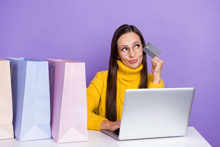 Photo of wondered woman look copyspace thinking shopping online use plastic card isolated on violet...