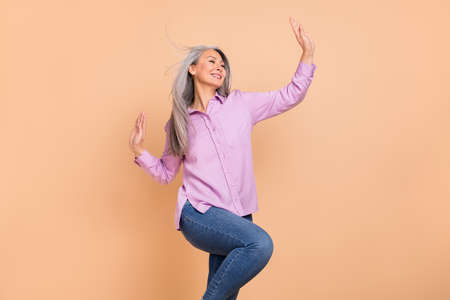Photo of cute white hairdo old lady dance wear violet outfit jeans isolated on beige background