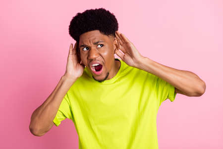 Photo of young african guy amazed shocked hands touch ears eavesdrop news rumor look empty space isolated over pink color backgroundの写真素材