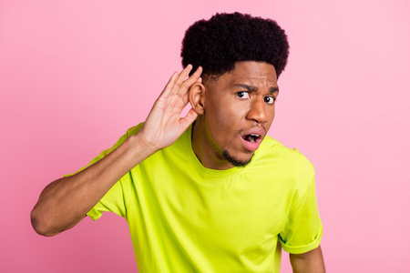 Photo of unhappy young dark skin man hold finger head ear listen rumor isolated on pink color backgroundの写真素材