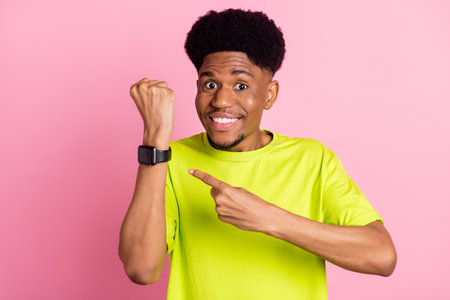 Photo of young african guy happy positive smile point finger smart watch device ad advice isolated over pink color backgroundの写真素材