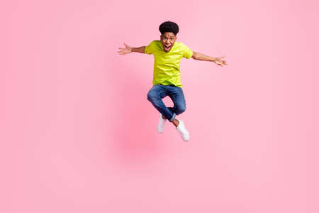 Full body photo of young cheerful african guy happy positive smile jump isolated over pink color backgroundの写真素材
