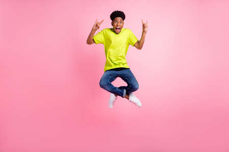 Full length body size view of attractive cheerful guy jumping showing horn symbol isolated over pink pastel color backgroundの写真素材