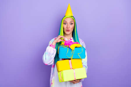 Photo of surprised lady hold stack boxes unwrap package wear cone cap kigurumi costume isolated violet color backgroundの写真素材