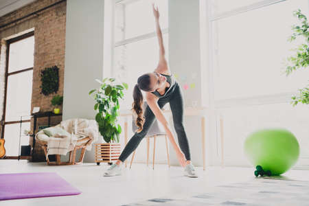 Photo of sexy strong young girl dressed sport suit doing wind mill exercise smiling indoors house homeの写真素材