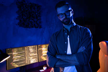 Portrait of serious experienced person folded hands look camera debugging optimization dark room business centerの写真素材