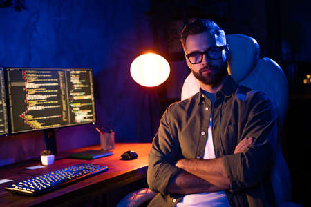 Photo of successful handsome guy crossed arms sit chair look camera lamp light evening dark loft spaceの写真素材