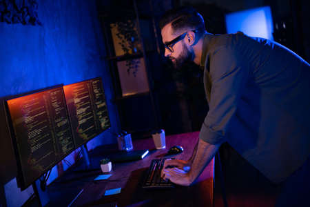 Profile portrait of smart clever professional typing keyboard look two displays testing edit dark evening loft spaceの写真素材