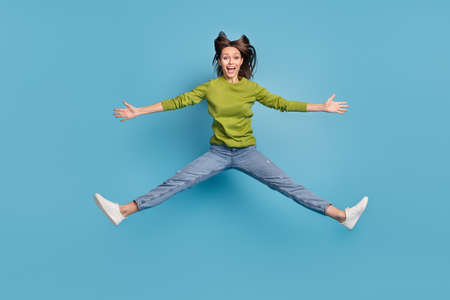 Photo of cheerful amazed shocked lady jump open mouth wear green shirt jeans footwear isolated blue...