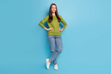 Photo of confident charming lady hands hips look camera wear green shirt jeans isolated blue color...
