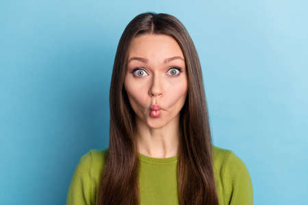 Photo of young funny girl pouted lips have fun carefree grimacing isolated over blue color backgroundの写真素材