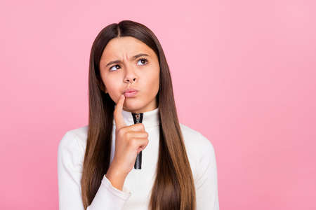 Photo of unsure brunette small girl look empty space wear white pullover isolated on pastel pink color backgroundの写真素材