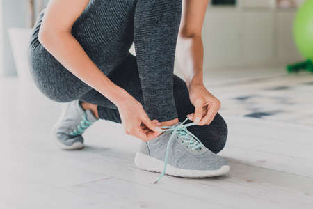 Cropped view of sportive girl doing sports tying cord on footwear prepare sprint staying safe at...