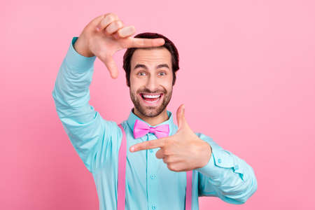 Photo of funny charming young man wear turquoise outfit smiling showing fingers photo shot isolated pink color backgroundの写真素材