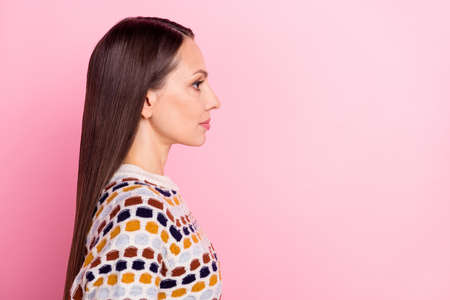 Photo of serious confident young woman wear dotted sweater looking empty space isolated pink color backgroundの写真素材