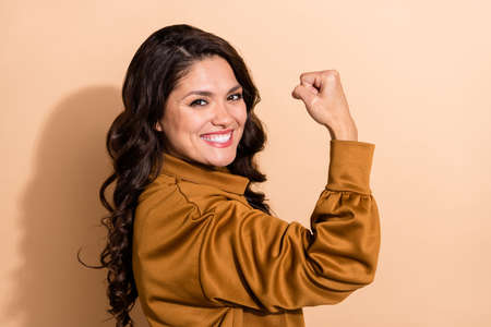 Profile side view portrait of attractive cheerful wavy-haired woman having fun great success isolated over beige pastel color backgroundの写真素材