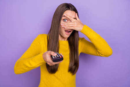 Photo of young pretty woman scared cover eyes hand watch horror movie isolated over purple color...