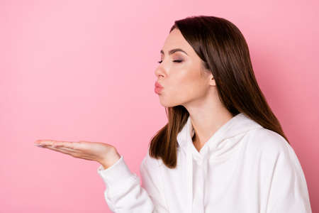 Photo of sweet adorable young woman dressed white sweatshirt sending liss arm empty space isolated pink color backgroundの写真素材