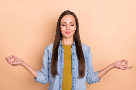 Portrait of young beautiful peaceful female doing yoga with closed eyes wear denim shirt isolated on...