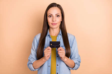 Photo of positive good-looking female hold credit card advertising product bank isolated on beige...