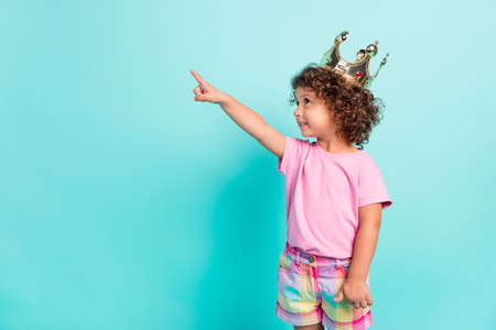 Profile side photo of young girl happy positive smile princess point finger empty space isolated over turquoise color backgroundの写真素材