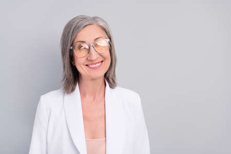 Photo of impressed white hairdo aged lady look empty space wear eyewear blazer isolated on grey...
