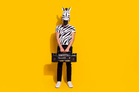 Full length photo of freak crazy unusual guy in zebra costume hold boom box isolated over yellow shine color backgroundの写真素材