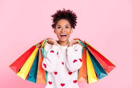 Photo of stylish impressed curly hairdo young lady hold bags look up wear white sweater isolated on...
