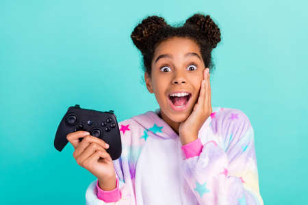 Photo of young excited afro girl hand touch cheek party sleepover play nightwear isolated over turquoise color backgroundの写真素材