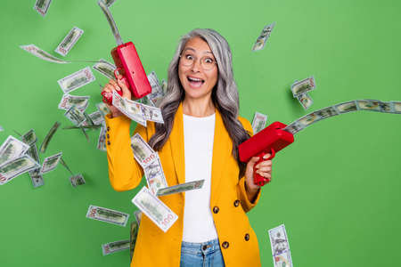 Photo of excited senior woman have fun waist money rich air cash isolated over green color...