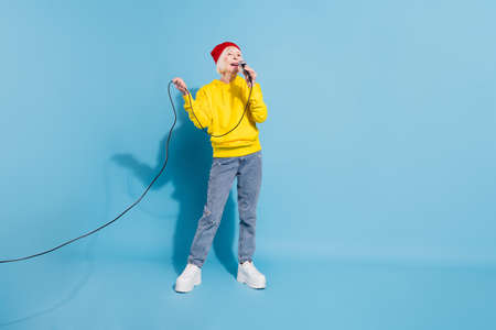 Full length photo of cheerful nice happy old woman sung karaoke enjoy isolated on pastel blue color backgroundの写真素材