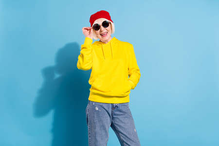 Photo of attractive positive old woman wear cool sunglasses red hat smile isolated on pastel blue color backgroundの写真素材