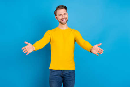 Photo of young guy happy positive smile open arms hug cuddle friendly invite isolated over blue...