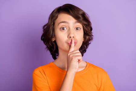 Portrait of attractive funny mysterious boy showing shh sign isolated over violet purple color backgroundの写真素材