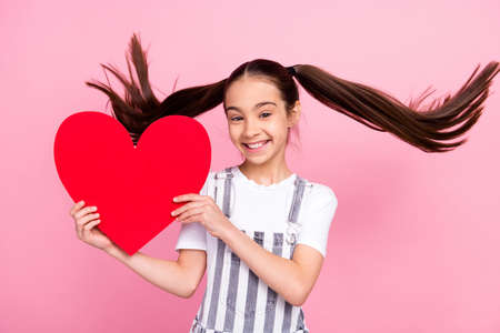 Photo of adorable happy pretty little girl good mood hold hands heart shape isolated on pink color backgroundの写真素材