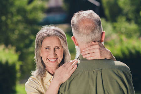 Back side photo of funny old couple hug wear shirt walk in park outside outdoorsの写真素材