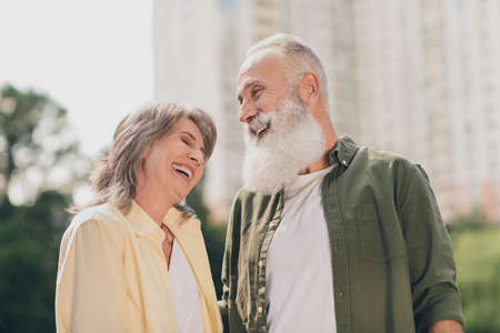 Photo of funky expression aged grey hair couple laugh together wear shirts outdoors day off in park