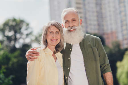 Photo of friendly elder grey hair couple hug wear shirts outdoors walk in parkの写真素材