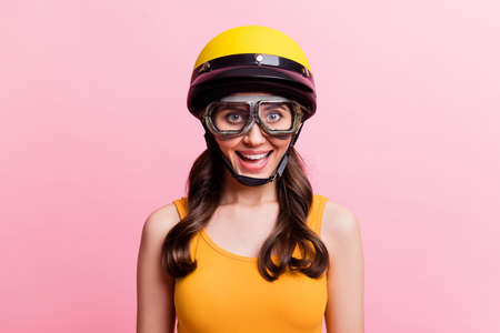 Photo of impressed driver teen lady wear orange top helmet spectacles isolated on pink backgroundの写真素材