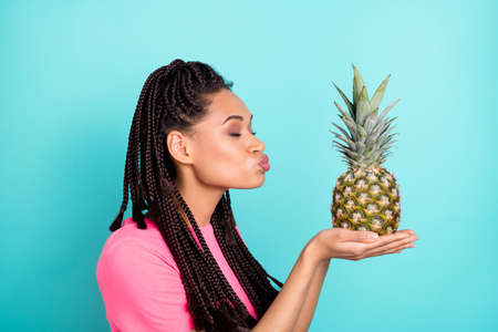 Profile photo of romantic girl hold ananas close eyes send air kiss wear pink t-shirt isolated on blue color backgroundの写真素材