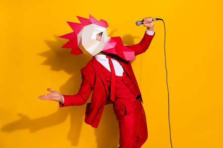 Photo of funny wacky guy sing mardi song performance wear rooster mask red tux isolated yellow color backgroundの写真素材