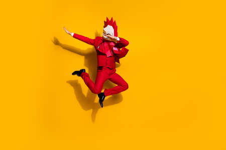 Photo of anonymous entertainer guy jump make dub wear cock polygonal mask red tux isolated yellow color backgroundの写真素材