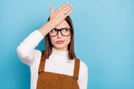 Photo of young attractive lady worried arm touch forehead thoughtful look empty space isolated over blue color backgroundの写真素材