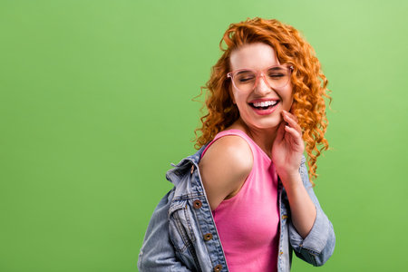 Photo of charming funny young lady dressed denim clothes glasses smiling laughing empty space isolated green color backgroundの写真素材